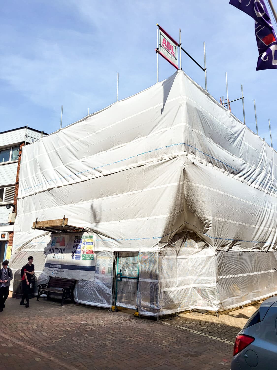 Commercial building fully enclosed in white shrink-wrap scaffolding on the Isle of Wight high street