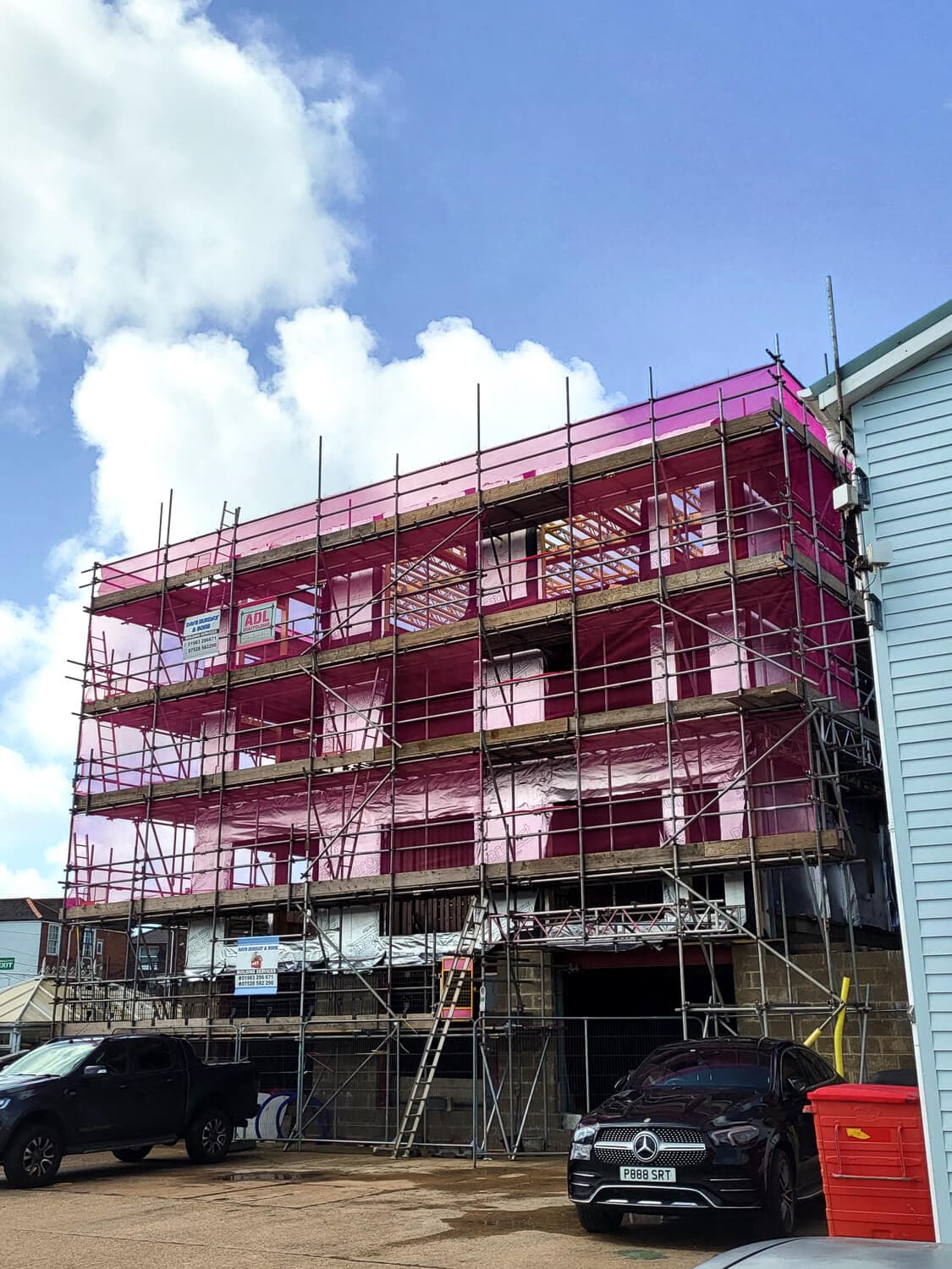 Multi-storey new-build commercial development with full scaffold and pink safety netting, Isle of Wight