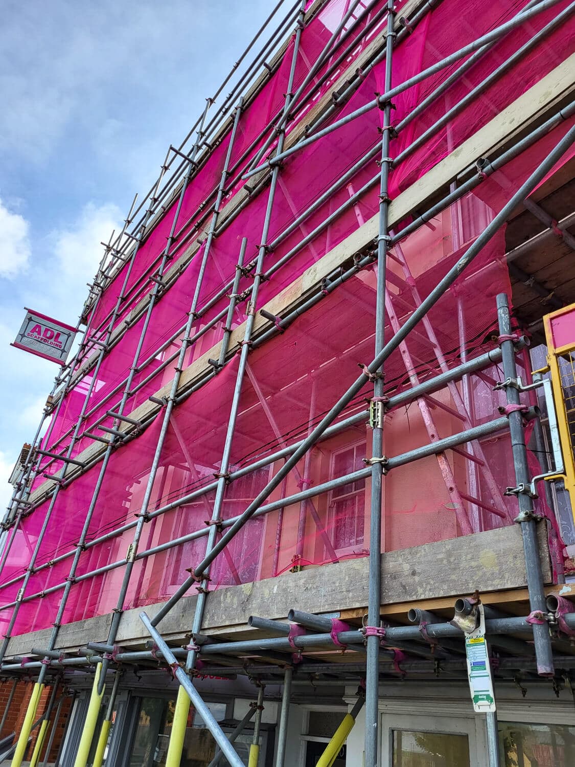 Close-up of ADL Scaffolding with brand pink safety netting on a commercial building, Isle of Wight