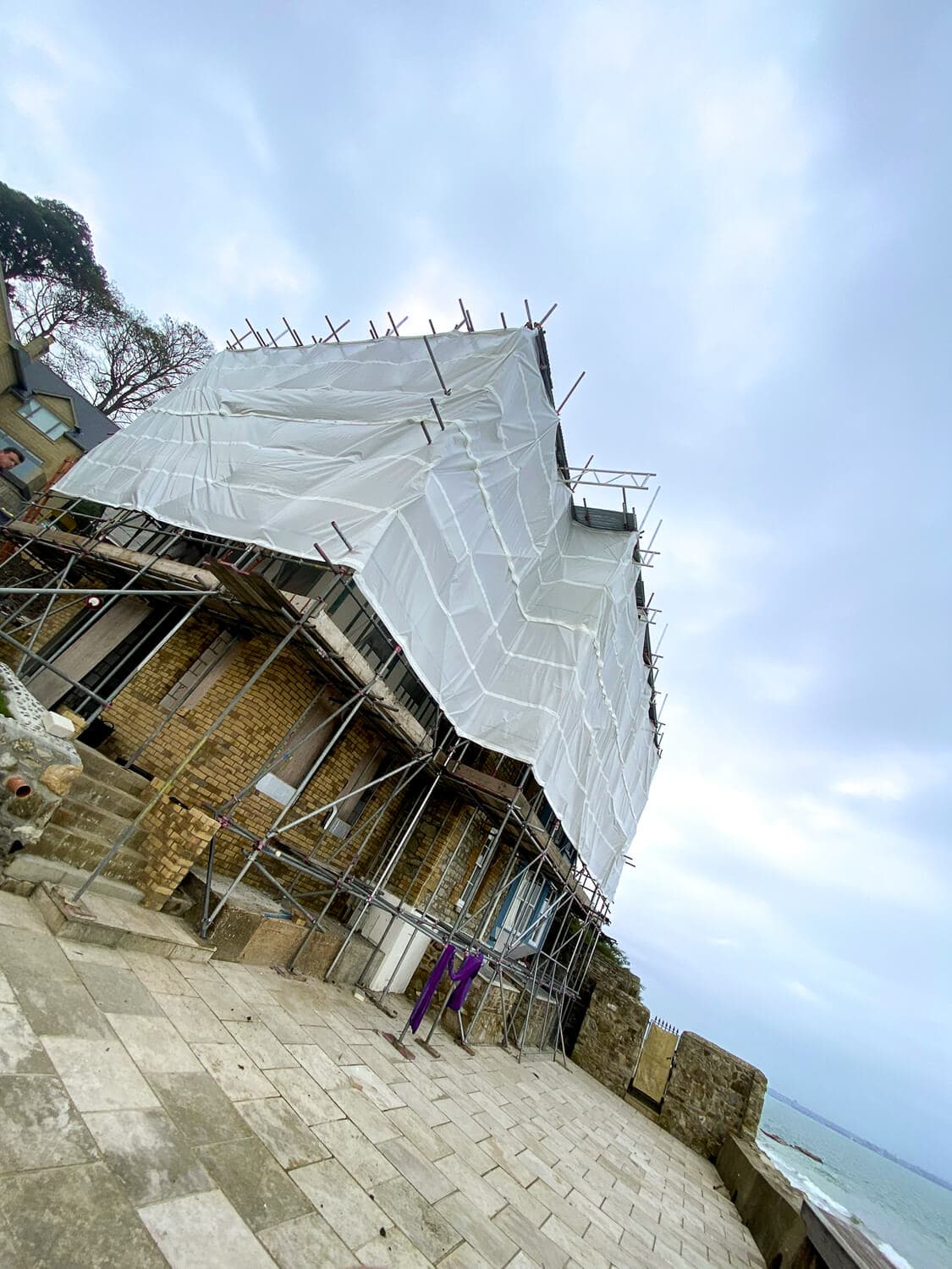 Scaffolding with shrink-wrap temporary roof on a coastal clifftop property, Isle of Wight