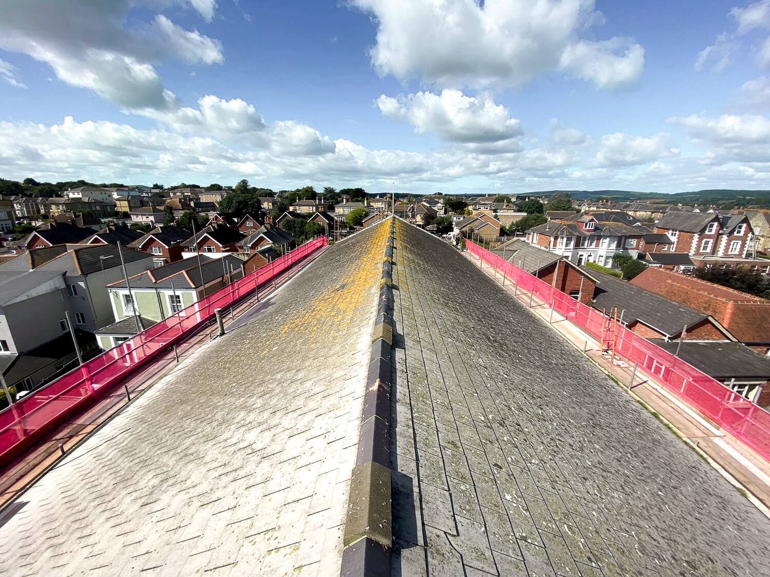 Aerial view along a large commercial roof with pink safety netting on both sides, Isle of Wight